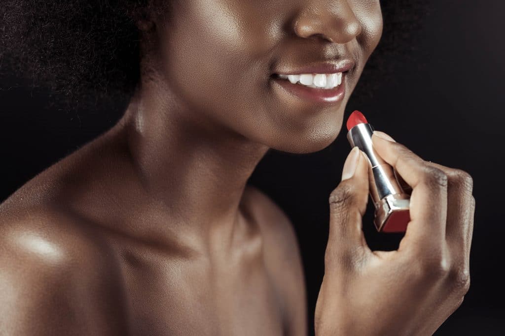African woman applying red lipstick