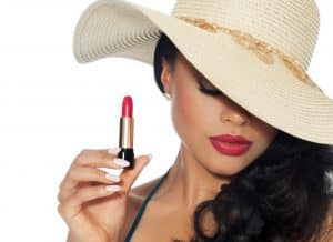 Beautiful woman in sunhat holding red lipstick