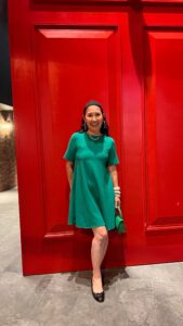 Woman in green dress standing in front of red background